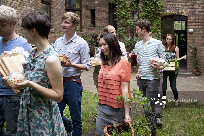 一群微笑的朋友携带食物参加花园派对图片素材