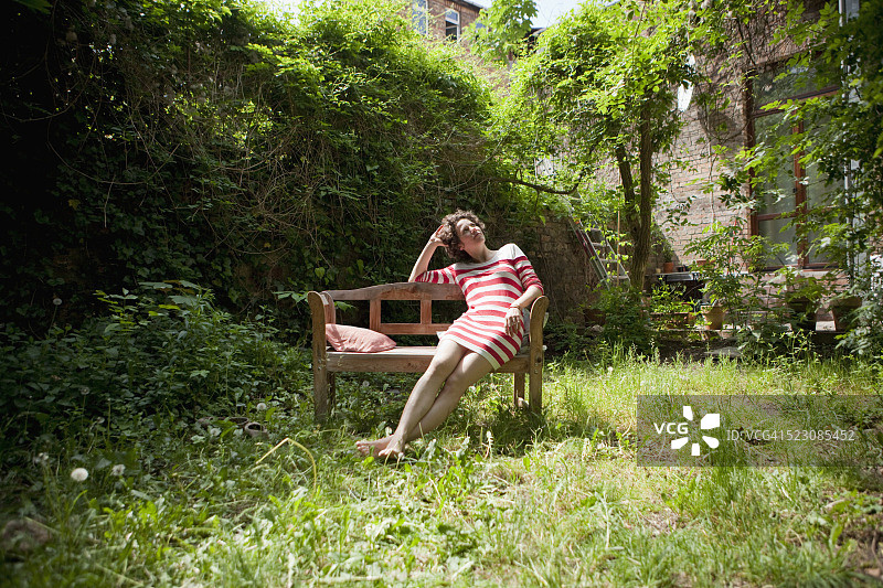女人坐在花园的长椅上图片素材