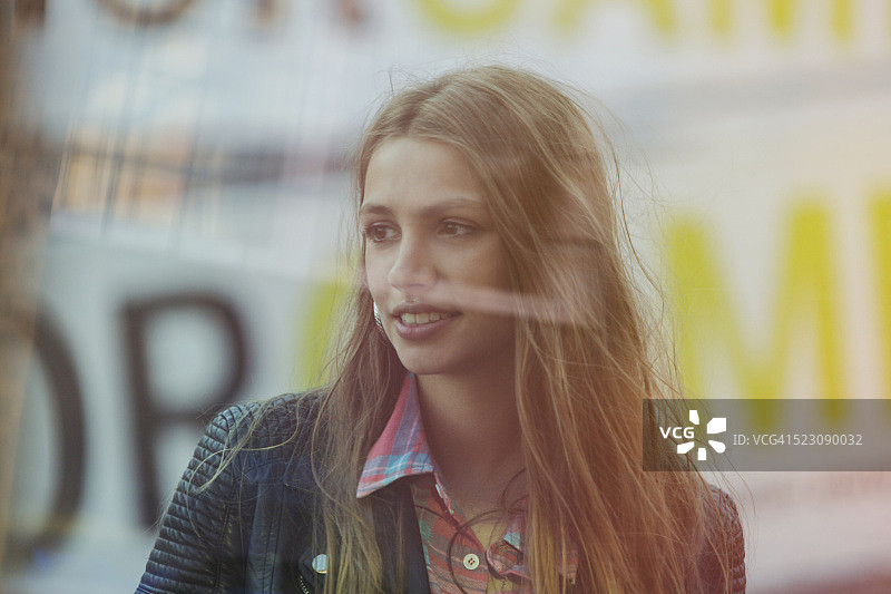 透过商店橱窗拍摄的年轻女子肖像图片素材