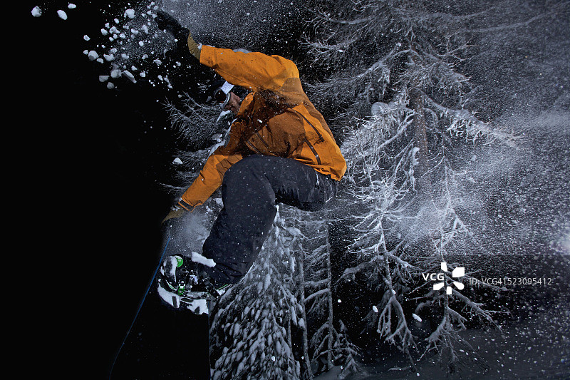 年轻的单板滑雪者夜晚森林中跳跃图片素材
