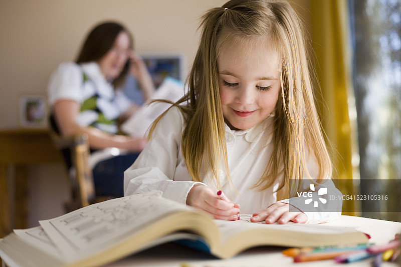 女孩涂色，母亲在一旁工作图片素材