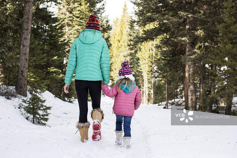 母亲和女儿(4-5岁)在蒙大拿州加拉廷县博兹曼的雪地上行走图片素材