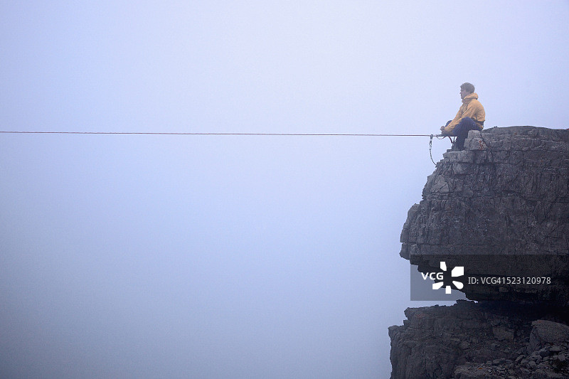 男子坐在奥地利蒂罗尔邦两块岩石之间的高空绳索前图片素材