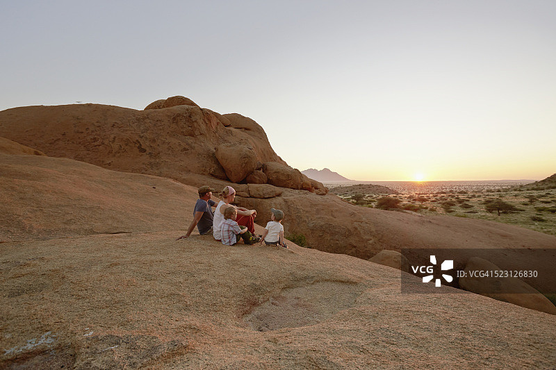 一家人坐在岩石上观看日落图片素材