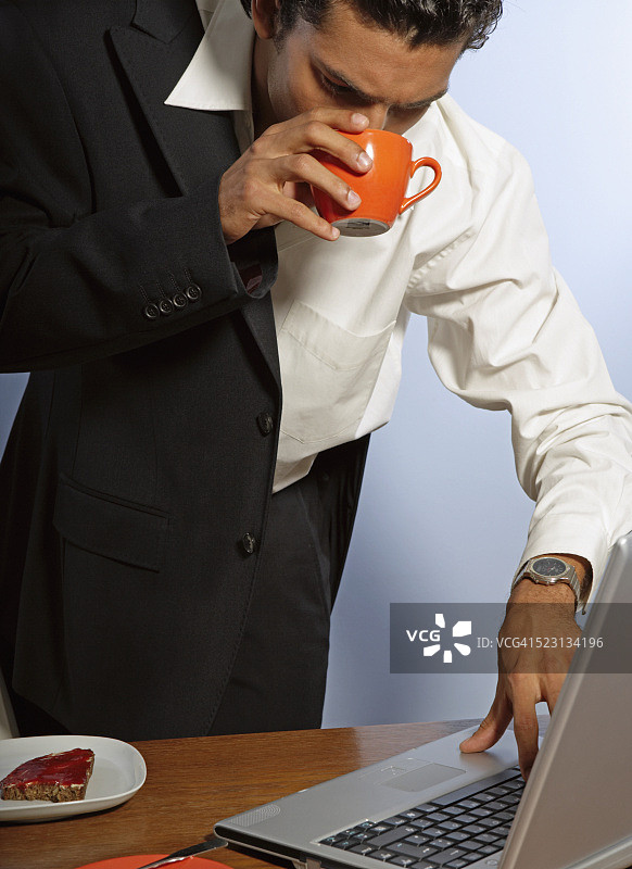 早餐时使用笔记本电脑的年轻商人图片素材