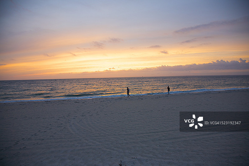情侣在科德角日落时分的海岸线行走图片素材