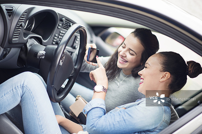 两名年轻女子在车内使用GPS导航，面带微笑图片素材