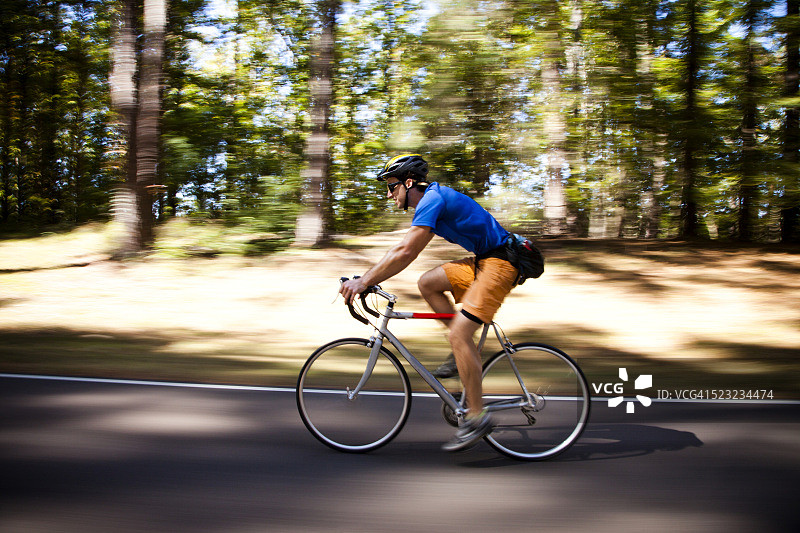 年轻健壮的男人在阳光明媚的日子里骑着公路自行车，美国密西西比州纳奇兹图片素材