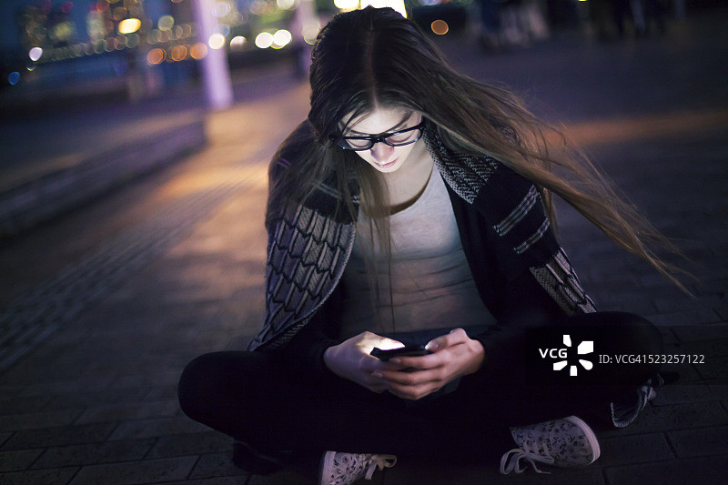 年轻女人坐在地上用手机打字图片素材