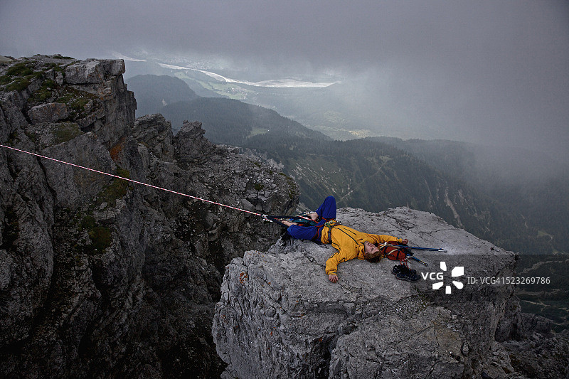 走过高空绳索后躺在岩石上的男人，奥地利蒂罗尔州图片素材