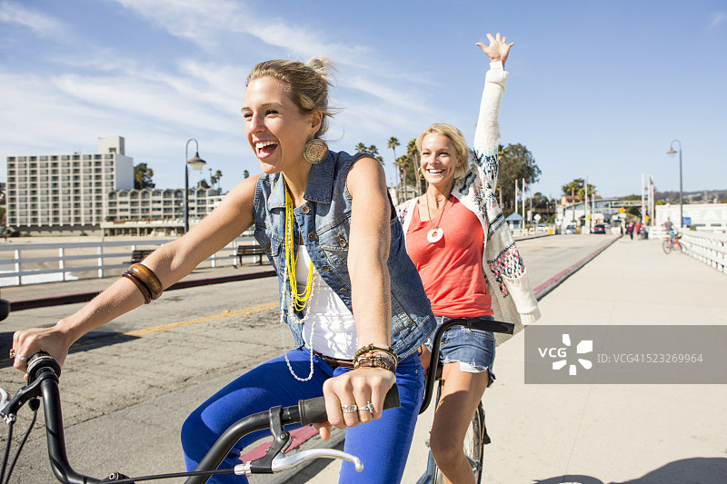 两个女人一起骑双人自行车，美国加利福尼亚州圣克鲁斯图片素材