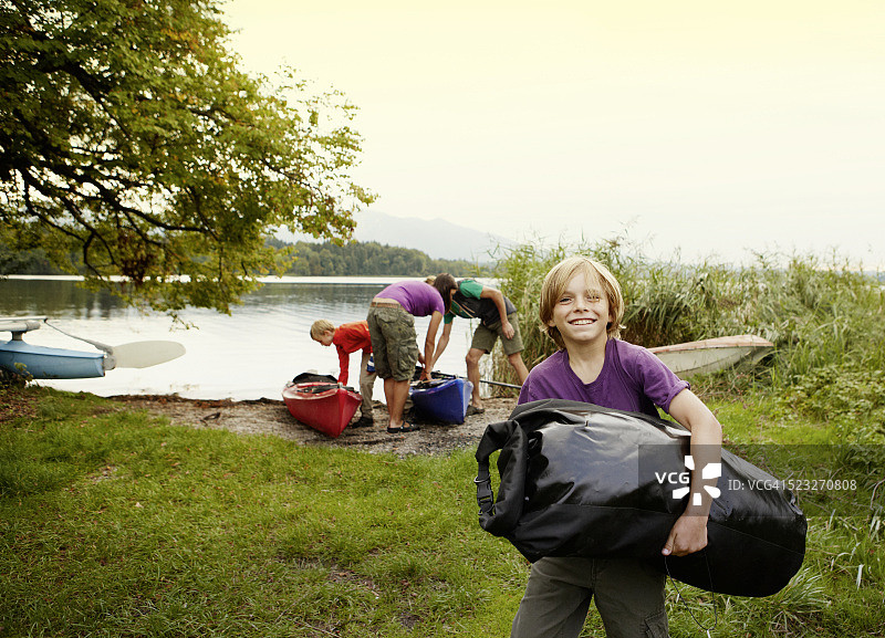 在德国巴伐利亚州穆尔瑙施塔费尔湖，父母和儿子（10-12岁）卸下独木舟图片素材