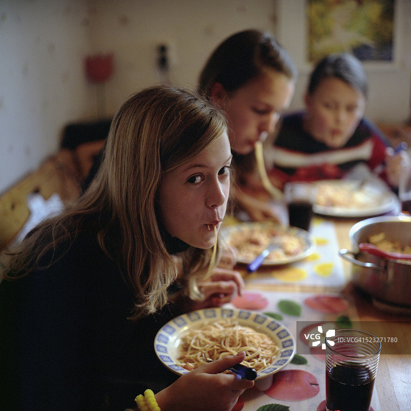 三个女孩在桌旁吃意大利面图片素材