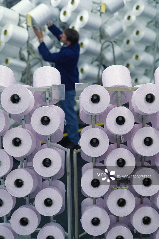 纺织工人前的合成纤维线轴图片素材