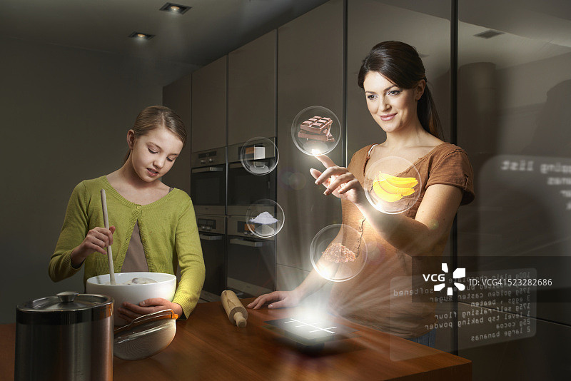 母女在厨房烹饪并使用未来设备图片素材