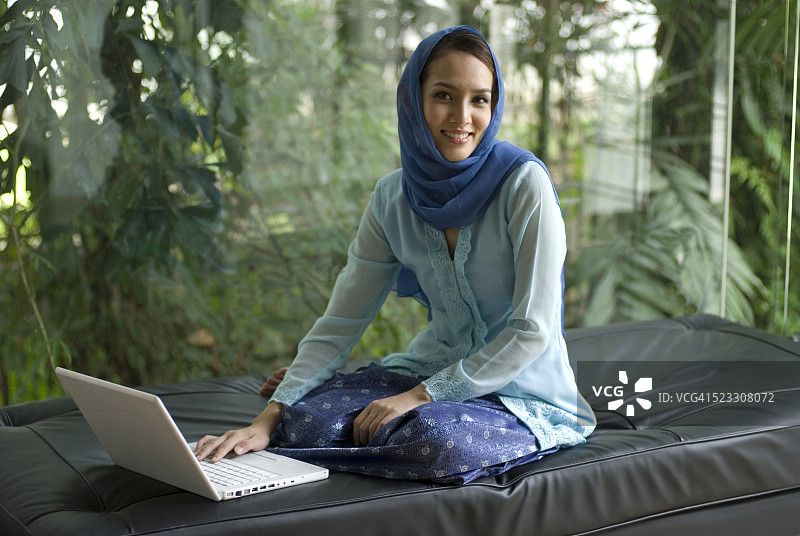 马来西亚穆斯林妇女在家使用笔记本电脑图片素材