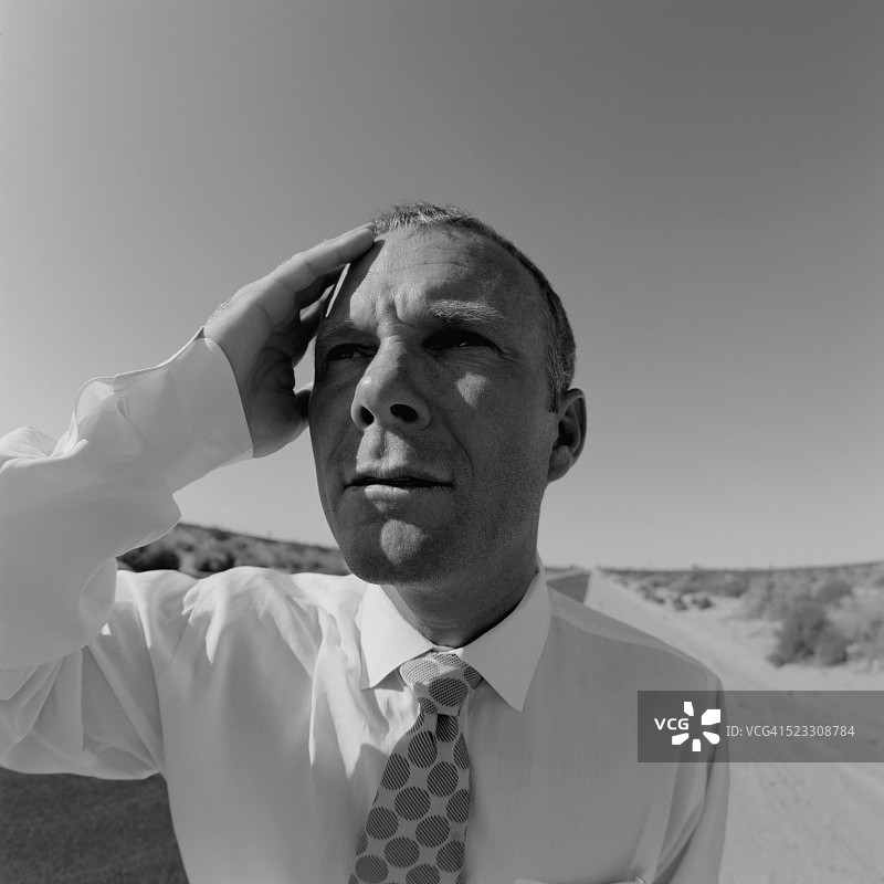 迷茫的商人站在荒凉的公路上图片素材