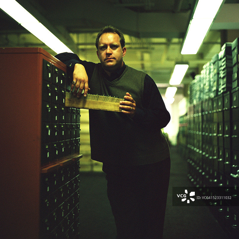 站在卡片目录前的男人图片素材