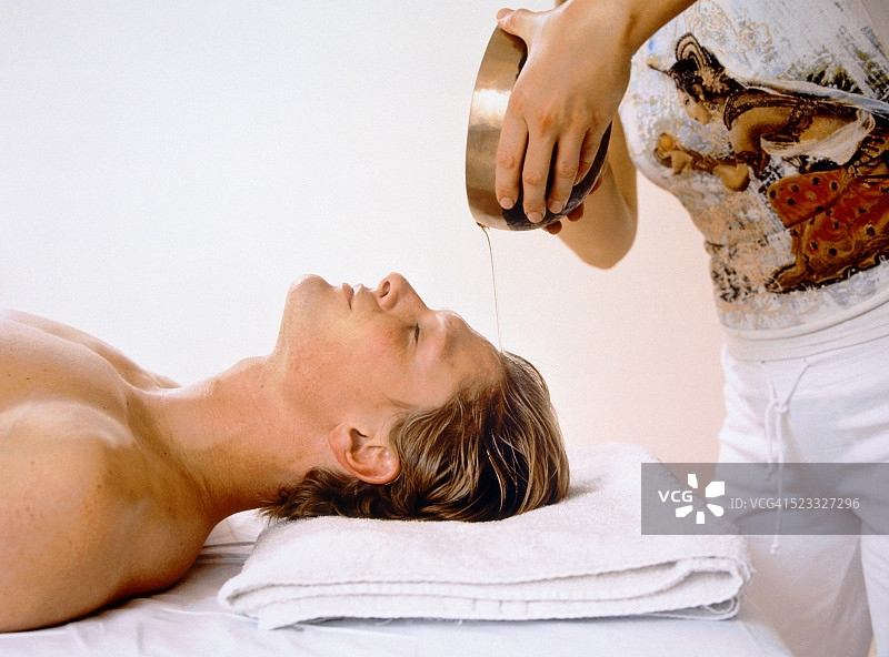 年轻男人接受阿育吠陀疗法图片素材