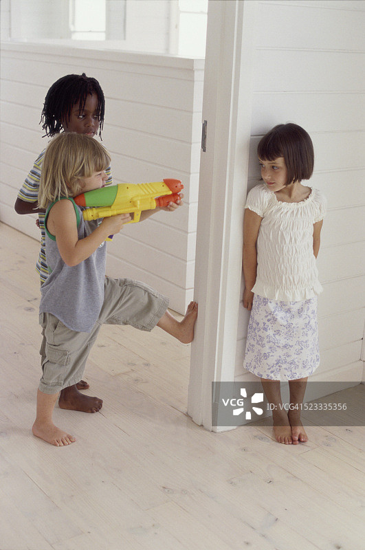 两个孩子用水枪射击女孩图片素材