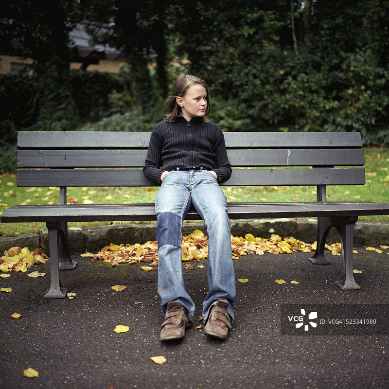 女孩坐在公园的长椅上图片素材