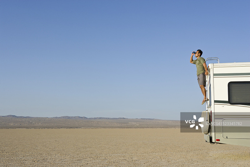 在沙漠中用双筒望远镜观察的男人图片素材