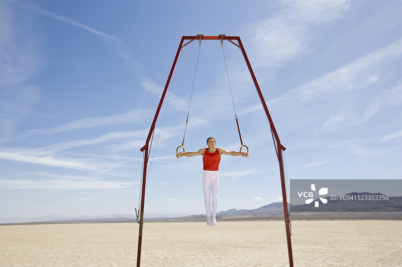 在沙漠中进行吊环表演的体操运动员图片素材