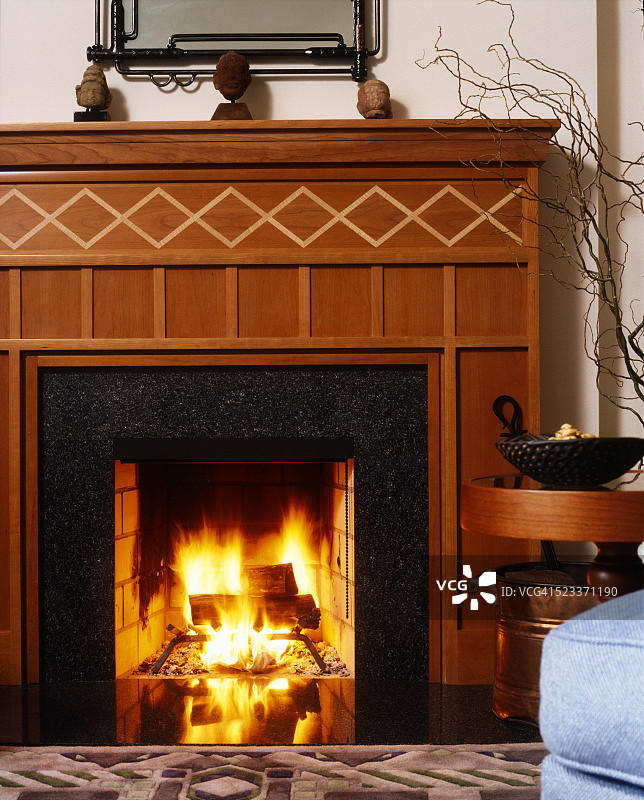花岗岩和镶嵌木壁炉架中燃烧的火焰图片素材