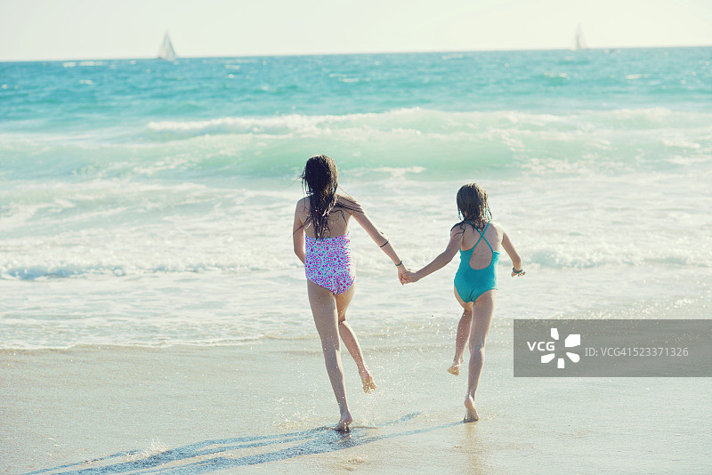 两个女孩手牵手奔向大海图片素材