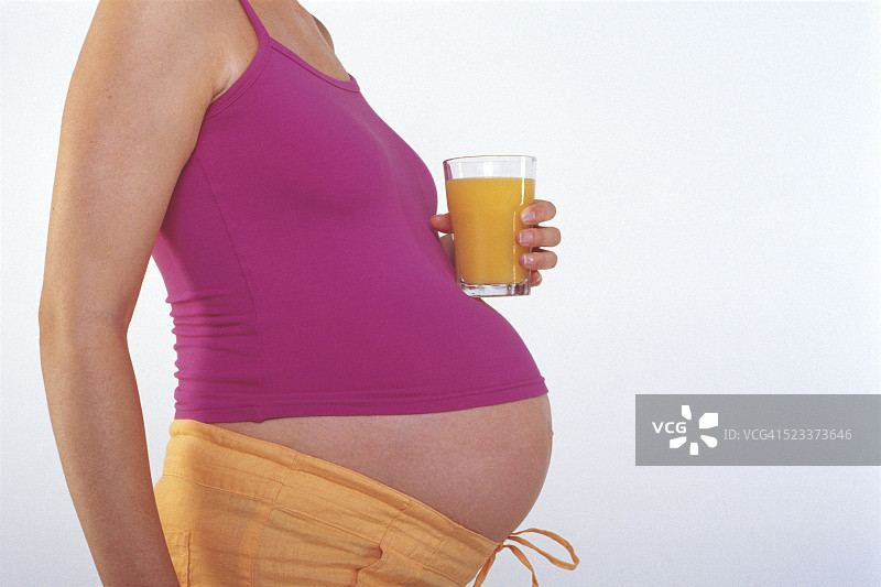 孕妇手拿橙汁看着肚子图片素材