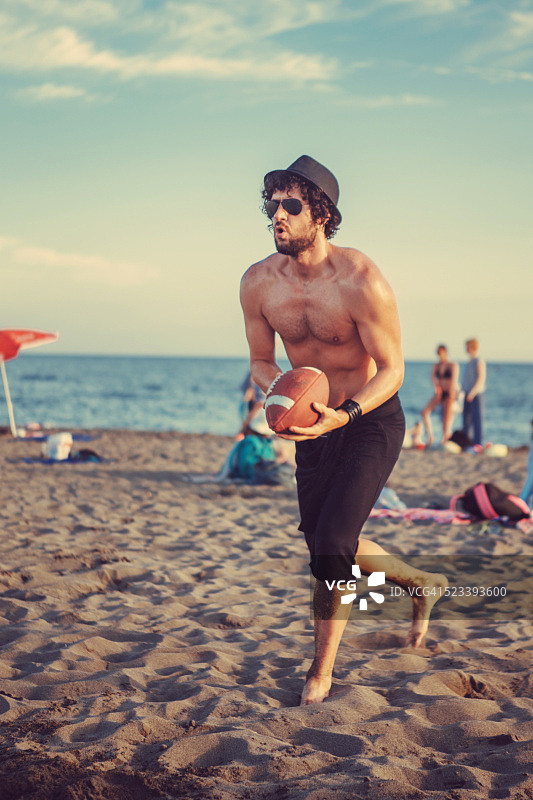在沙滩上接橄榄球的男人图片素材