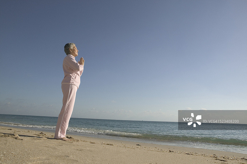 中年妇女在海滩上练习瑜伽图片素材