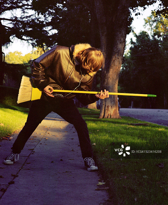 少年拿着扫帚弹奏空气吉他图片素材