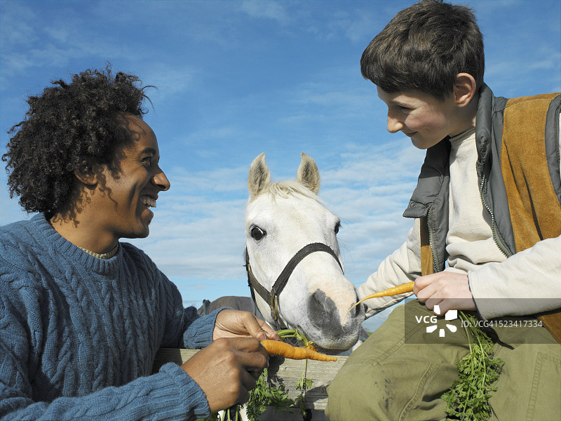 男子和男孩喂马吃胡萝卜图片素材