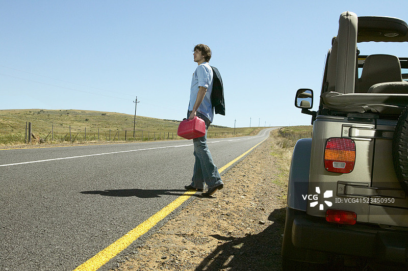 拿着汽油桶，远离汽车的男人图片素材