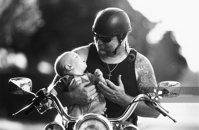 有纹身的骑自行车的人抱着一个婴儿图片素材