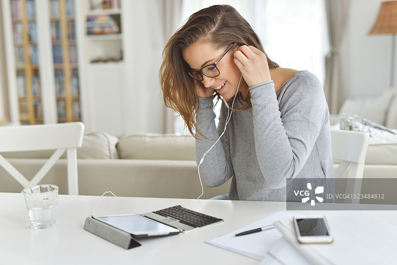 她正在使用带键盘和耳机的平板电脑图片素材