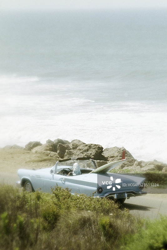 驾驶老式福特雷鸟汽车、携带冲浪板的女人图片素材