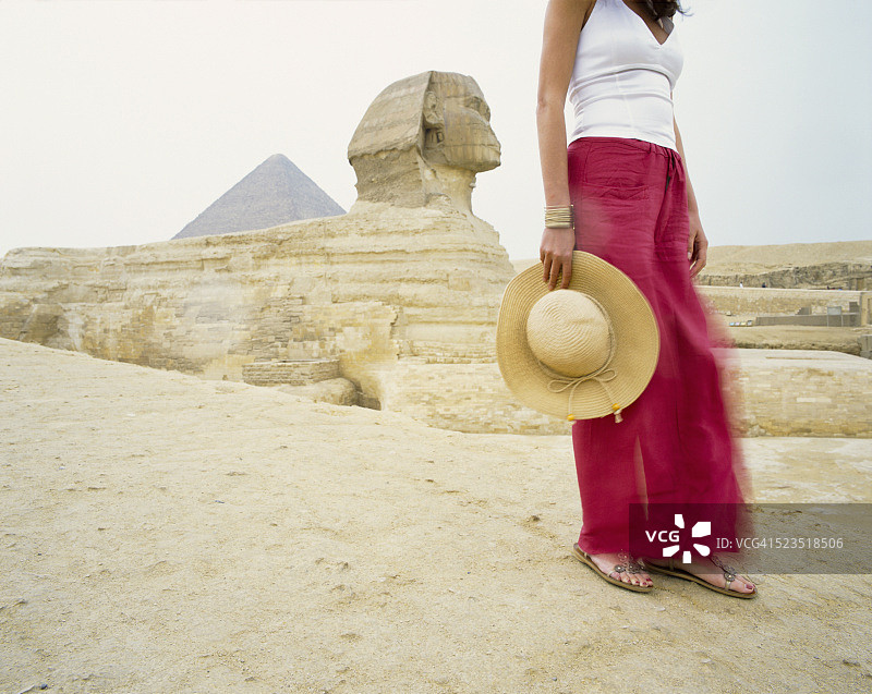 在狮身人面像和胡夫金字塔前的年轻女人图片素材