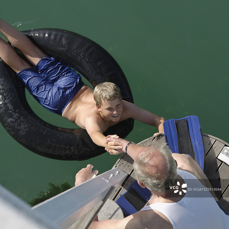 爷爷和孙子带着内胎离开码头图片素材