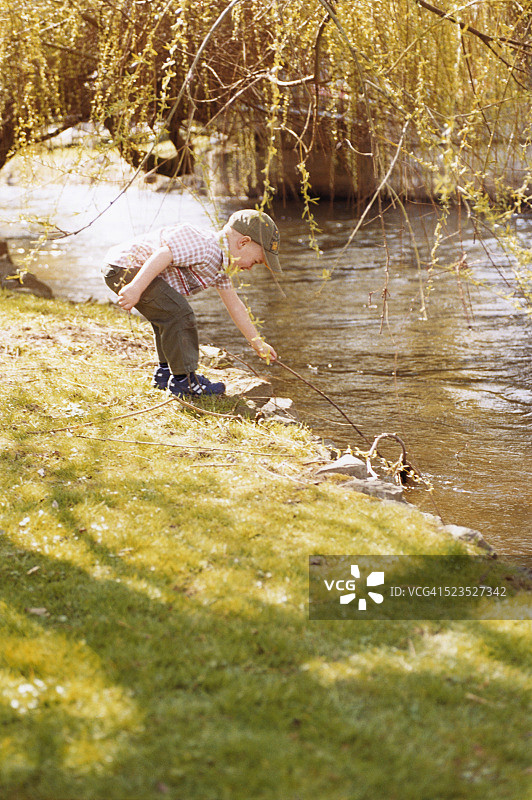 在水边玩棍子的男孩图片素材