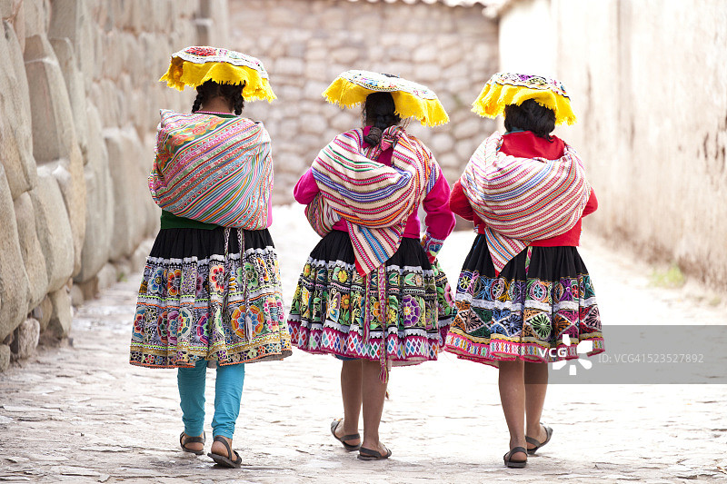 身穿传统服饰的三名女性途经秘鲁库斯科的印加残墙图片素材