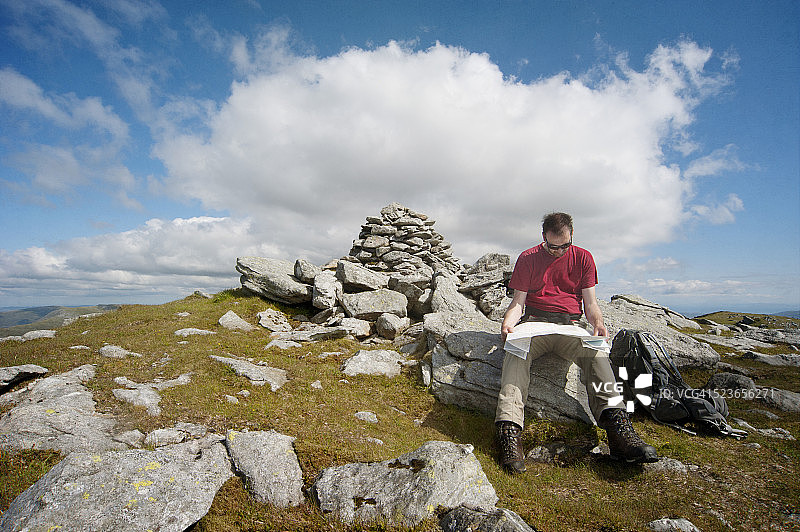 徒步旅行者在苏格兰山顶石堆附近阅读地图图片素材