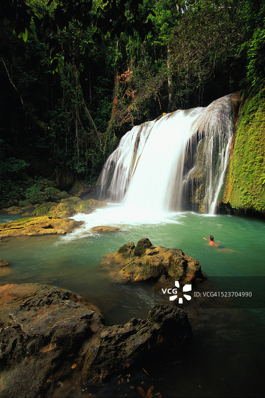 男人在牙买加Y.S.瀑布附近游泳图片素材