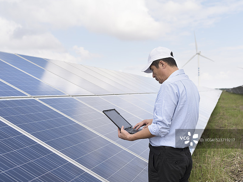 在太阳能发电厂使用笔记本电脑的亚洲男人图片素材