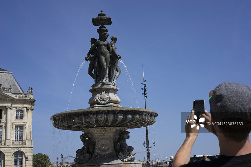 男子在法国波尔多交易所广场（皇家广场）拍照图片素材