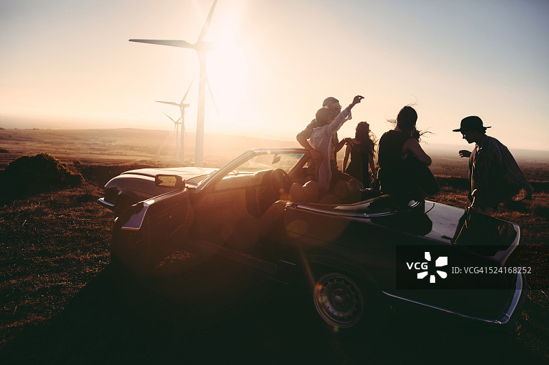 年轻的朋友们在日落时一起弹吉他，享受美好时光图片素材