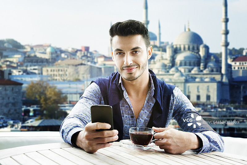 在伊斯坦布尔游轮上用手机自拍的土耳其帅气男人图片素材