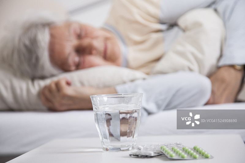 床头柜上的药丸和正在睡觉的老年妇女图片素材