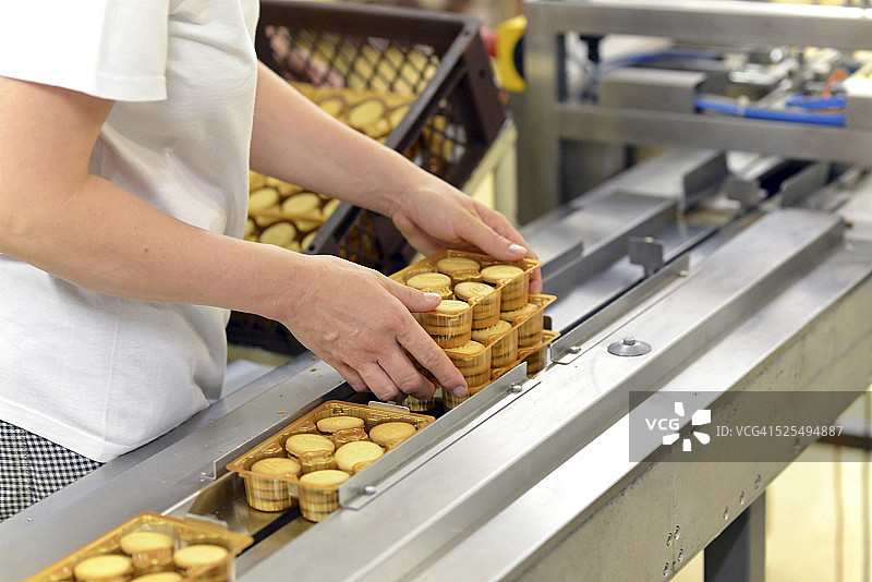 德国萨克森-安哈尔特州，女子在烘焙工厂的生产线上取饼干，局部视图图片素材